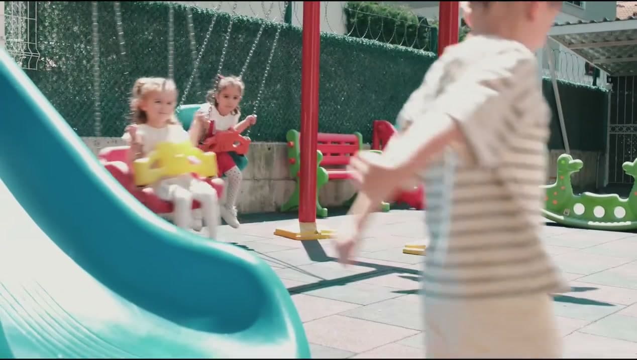 Oyun bahçesinde salıncakta sallanan çocuklar ve kaydırak