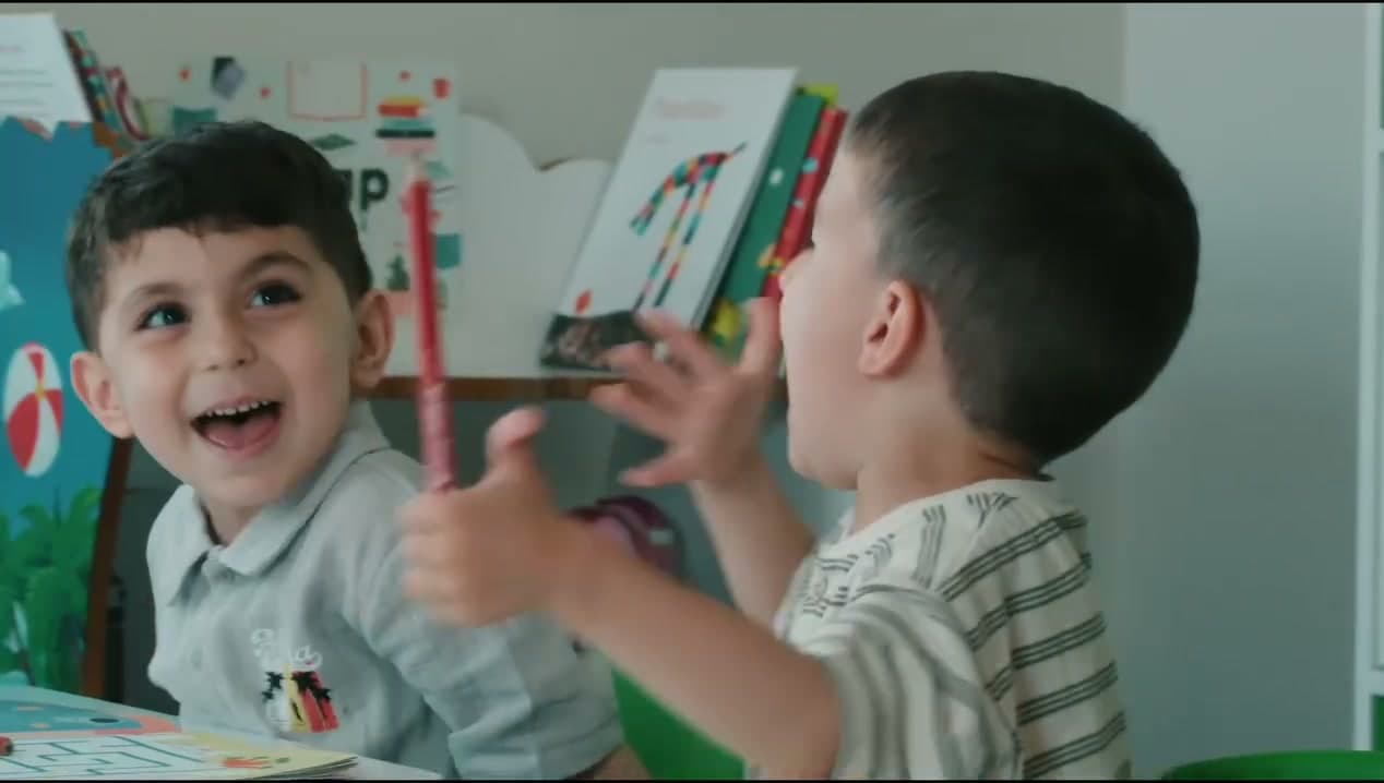 İngilizce kitabıyla gülerek el kaldıran iki erkek çocuk