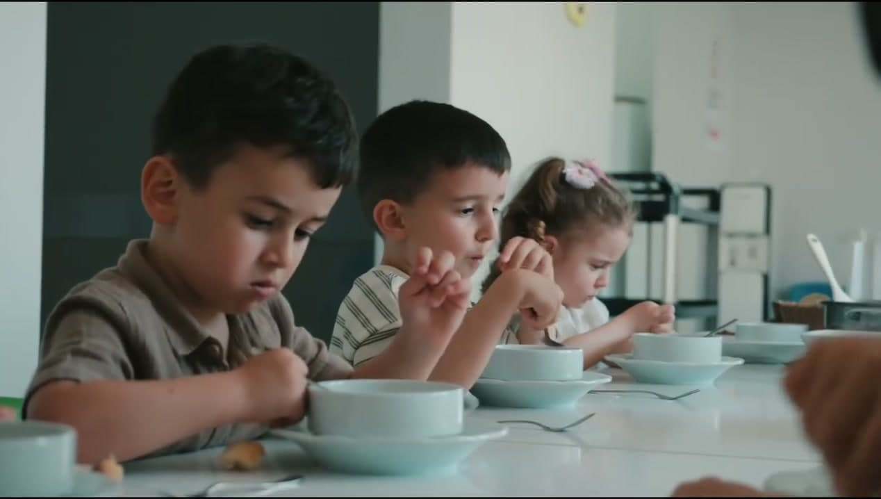 Yemekhanede masada birlikte yemek yiyen çocuklar